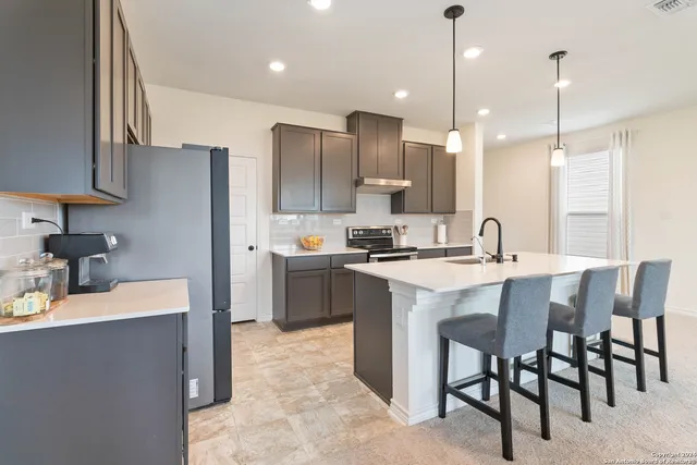 a kitchen with kitchen island a sink stove and refrigerator