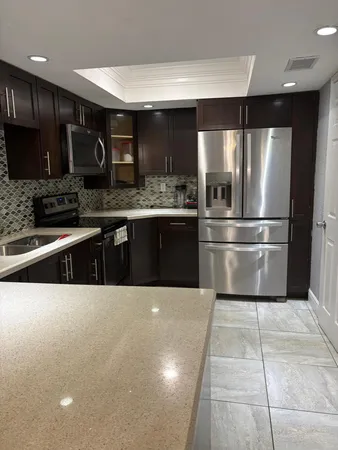 a large kitchen with stainless steel appliances kitchen island granite countertop a stove a sink and a refrigerator