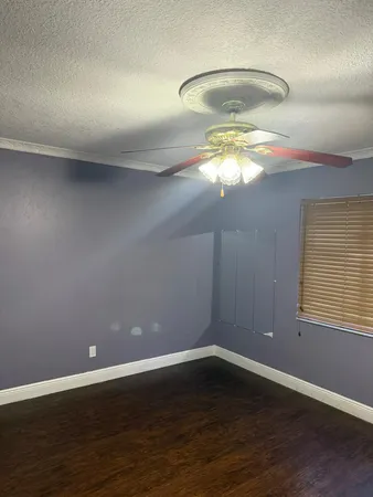 a view of an empty room with wooden floor and a chandelier