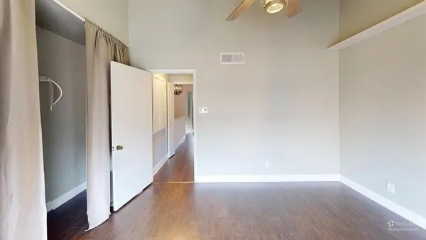a view of an empty room with wooden floor and a bathroom