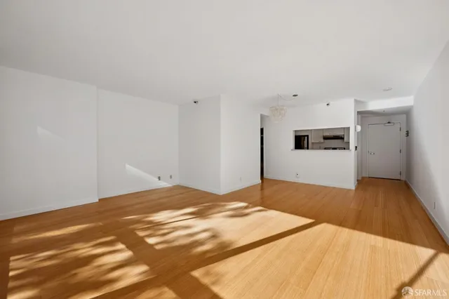 a view of a livingroom with wooden floor and kitchen