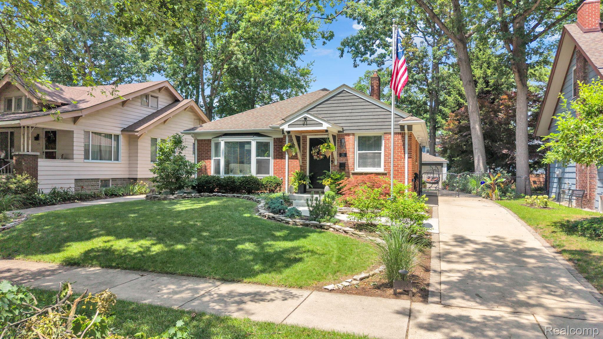 21 Devonshire Road Pleasant Ridge, MI 48069 - Photo 1 of 35 Brick facade home featuring a bay window, gabled roofline, mature trees, a well-maintained lawn, and a concrete driveway