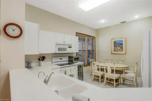 a kitchen with stainless steel appliances a sink a stove a table and chairs