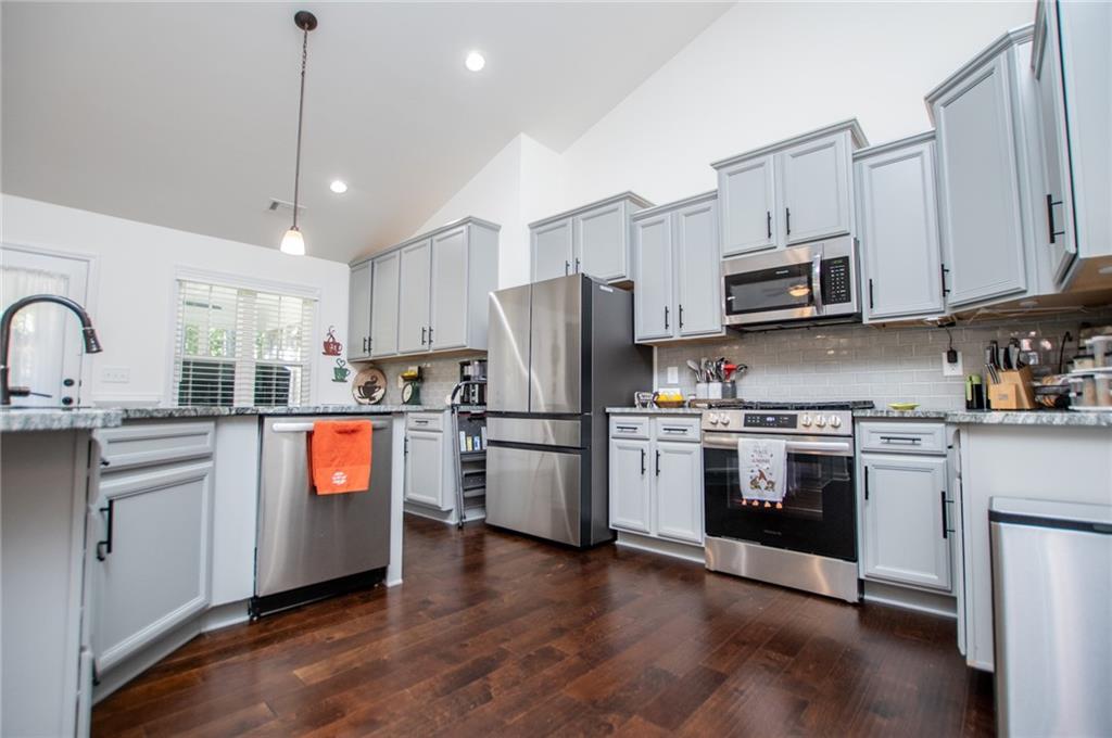 142 Lawrence Drive Villa Rica, GA 30180 - Photo 26 of 80 a kitchen with stainless steel appliances granite countertop a refrigerator a sink dishwasher a stove top oven a refrigerator with white cabinets and wooden floor