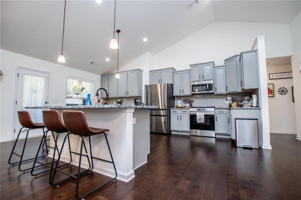 142 Lawrence Drive Villa Rica, GA 30180 - Photo 27 of 80 a kitchen with stainless steel appliances kitchen island granite countertop a stove a sink a refrigerator and white cabinets with wooden floor
