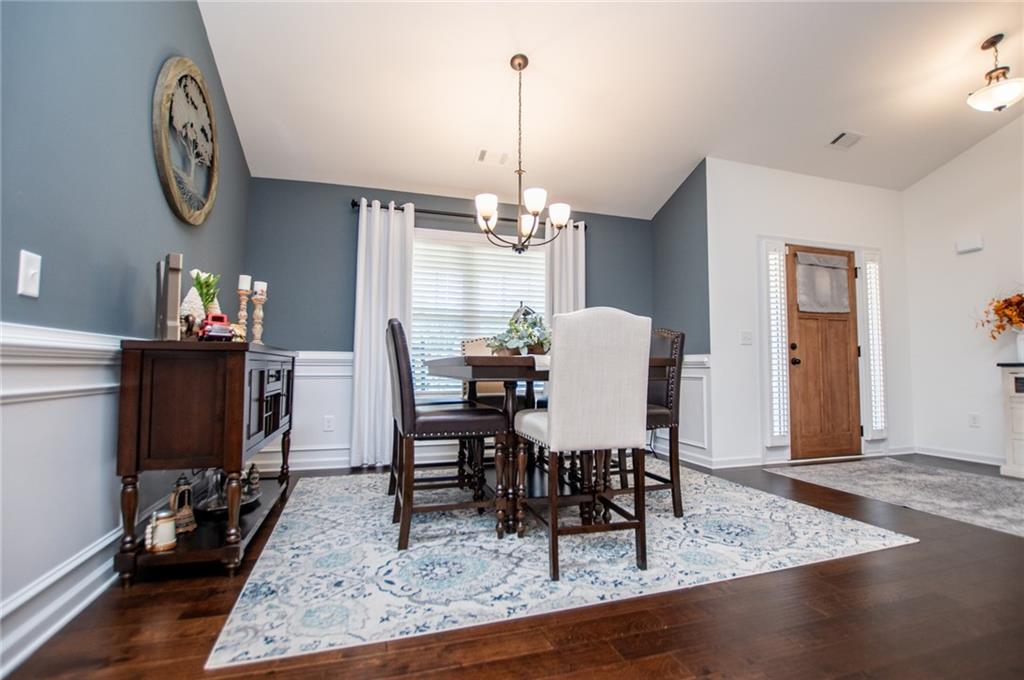 142 Lawrence Drive Villa Rica, GA 30180 - Photo 31 of 80 a dining room with wooden floor a chandelier a wooden table and chairs