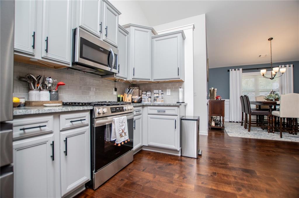 142 Lawrence Drive Villa Rica, GA 30180 - Photo 9 of 80 a kitchen with stainless steel appliances granite countertop a refrigerator a stove top oven a sink dishwasher and white cabinets with wooden floor