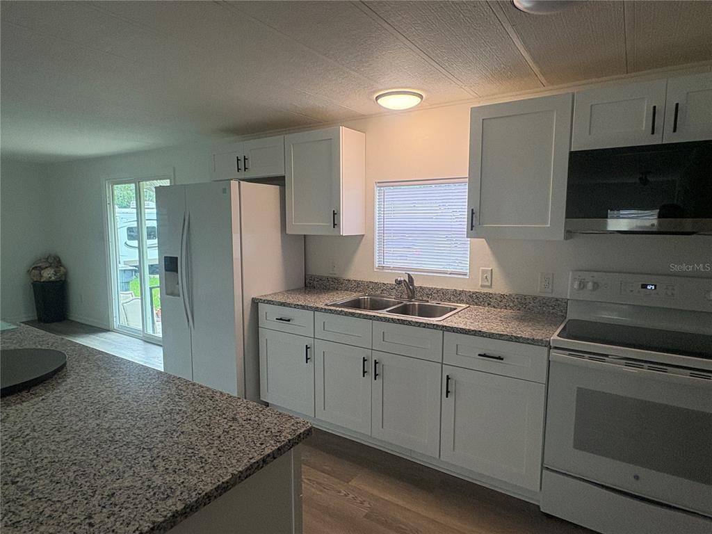 3923 Ward Road Lakeland, FL 33810 - Photo 12 of 25 a kitchen with granite countertop cabinets sink and stainless steel appliances
