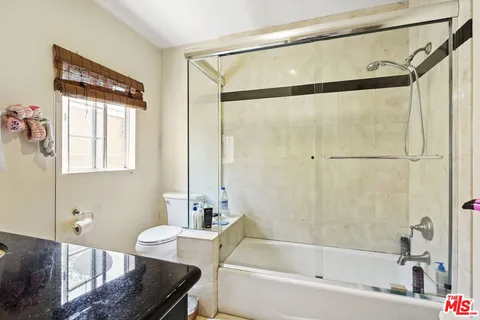 a bathroom with a granite countertop bathtub shower sink vanity and toilet