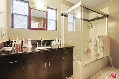 a bathroom with a sink a mirror a glass door and shower