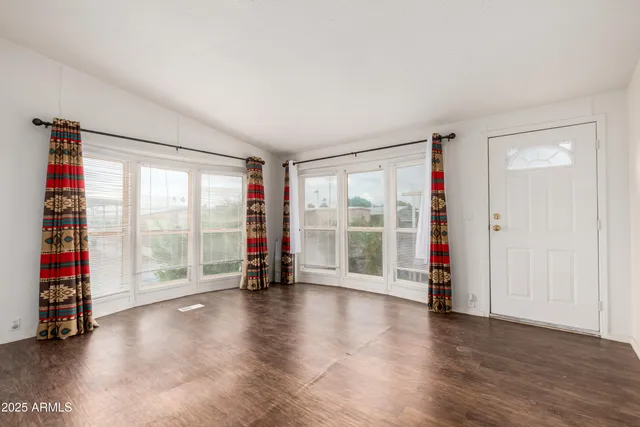 a view of an empty room with wooden floor and a floor to ceiling window
