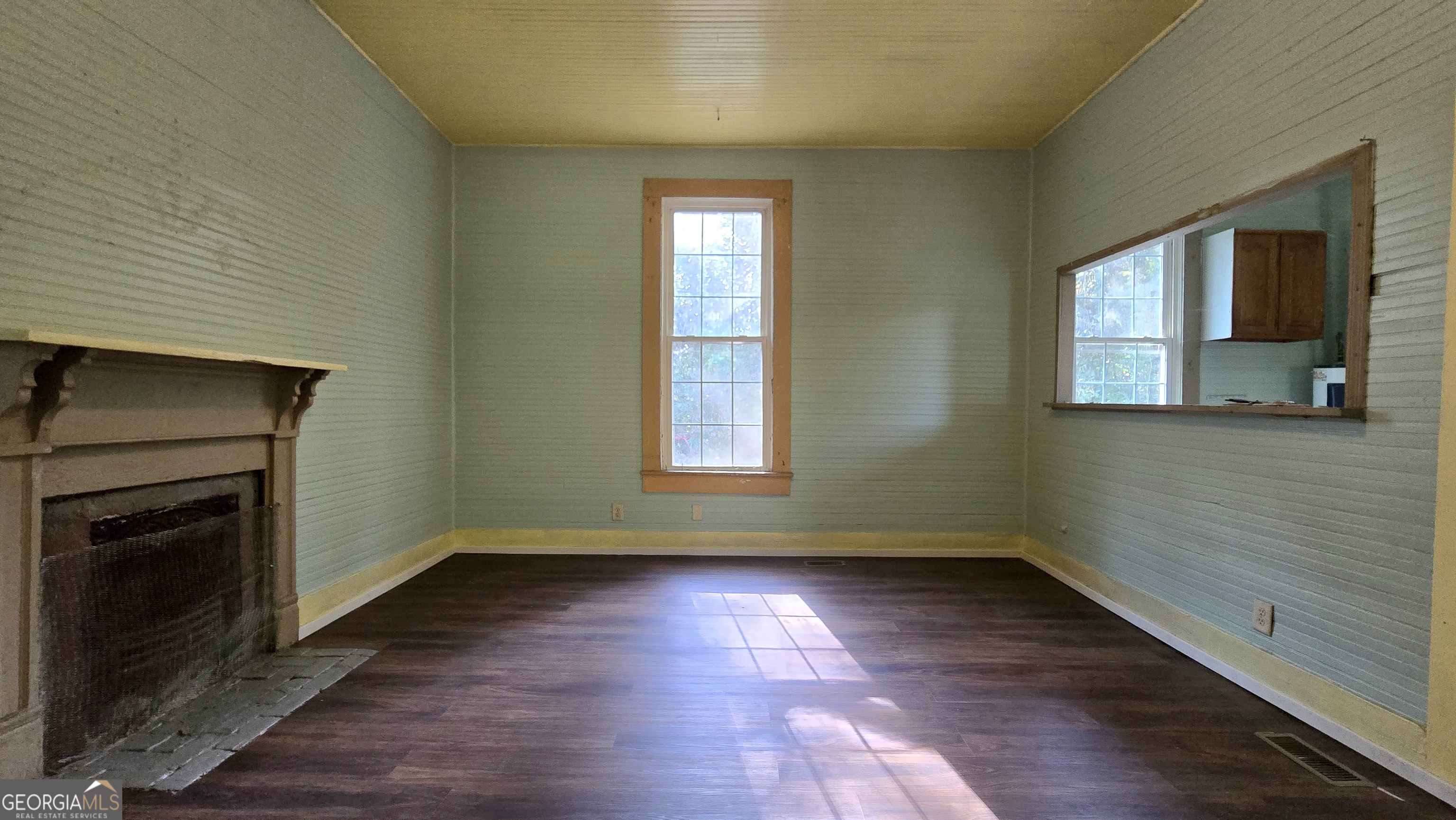509 Anderson Avenue Fort Valley, GA 31030 - Photo 8 of 22 an empty room with wooden floor a fireplace and windows