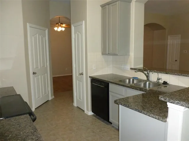 a kitchen with a granite countertop sink and cabinets