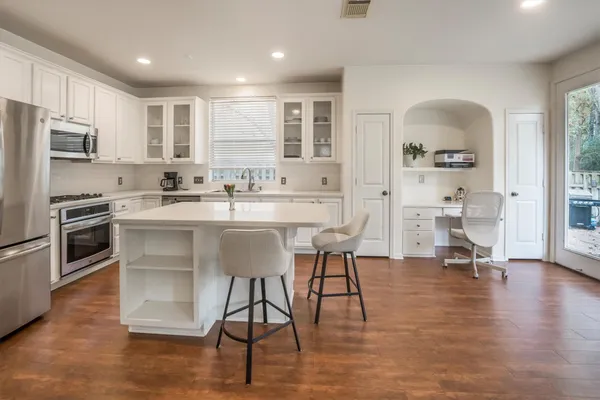 a kitchen with stainless steel appliances kitchen island granite countertop a stove a sink a refrigerator cabinets and a dining table with wooden floor