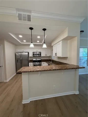 a large kitchen with stainless steel appliances a large counter top a stove a sink and a refrigerator