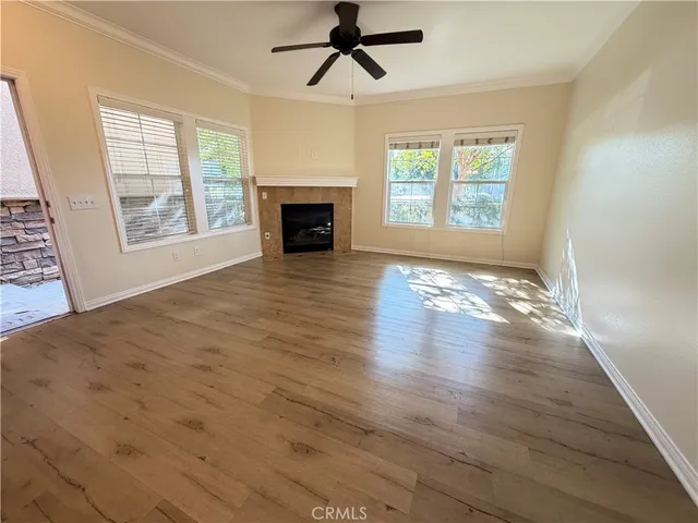 an empty room with windows fireplace and wooden floor