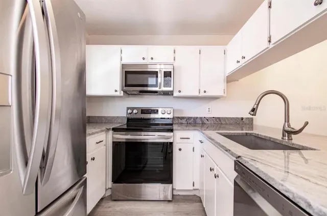 a kitchen with stainless steel appliances granite countertop a stove sink and refrigerator