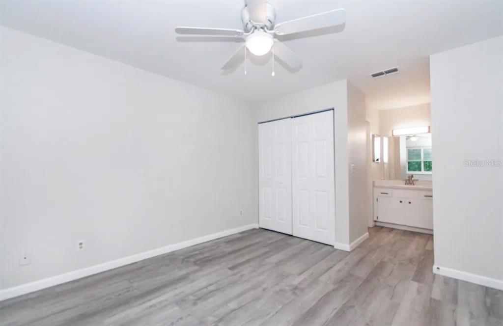39132 County Road 54, Unit 2180 Zephyrhills, FL 33542 - Photo 8 of 19 an empty room with wooden floor and a ceiling fan