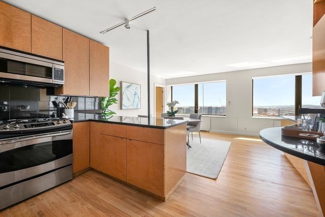 a kitchen with stainless steel appliances granite countertop a refrigerator a stove a oven with white cabinets and wooden floor