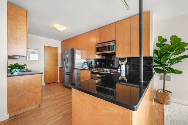 a kitchen with stainless steel appliances granite countertop a sink a stove and a wooden floors