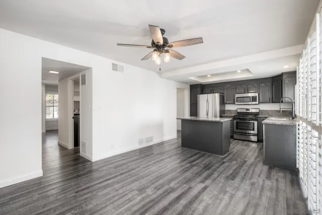 a kitchen with stainless steel appliances a refrigerator a stove top oven a sink dishwasher and a dining table with wooden floor