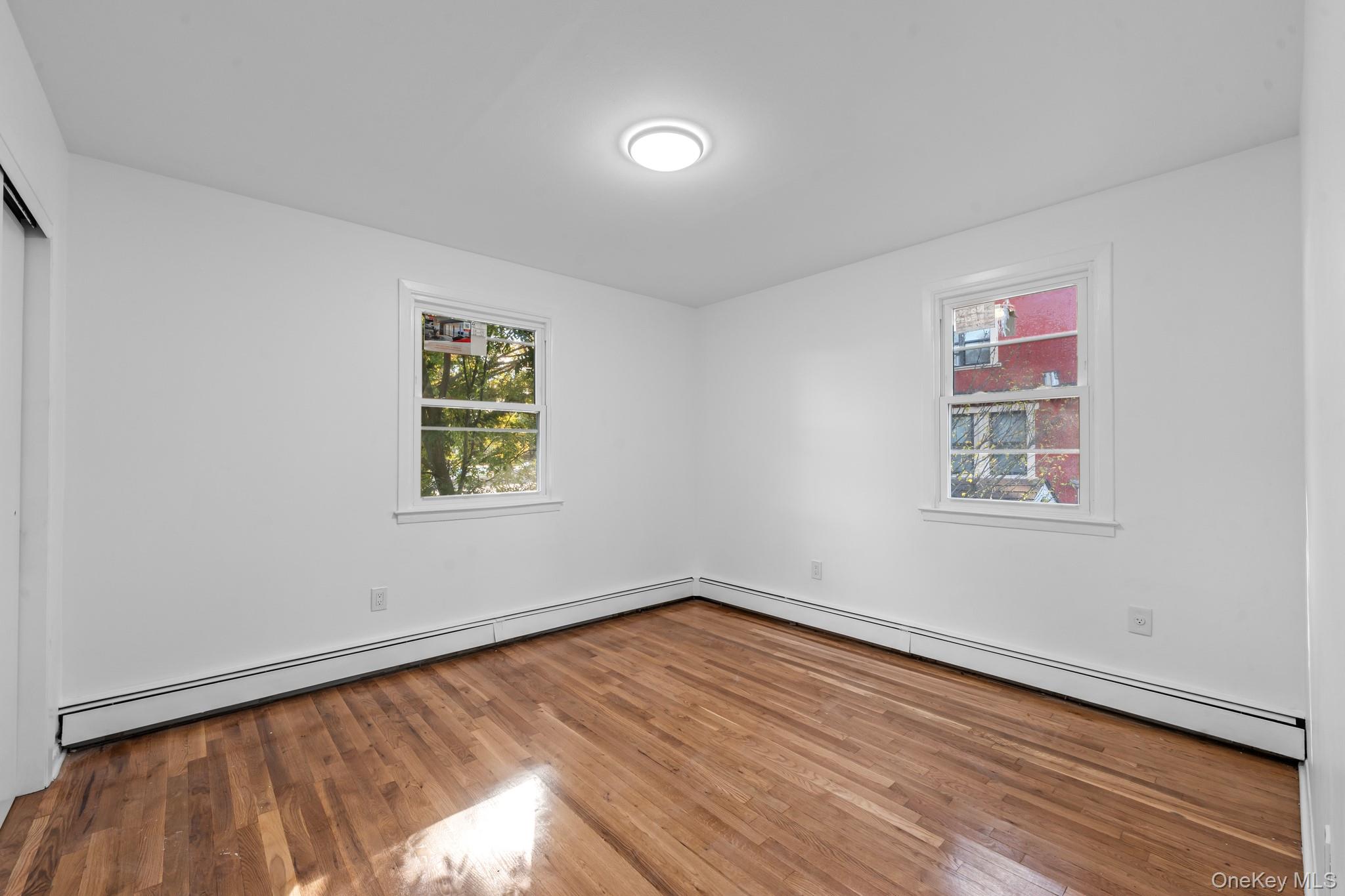 172-11 Horace Harding Expressway Queens, NY 11365 - Photo 13 of 17 a view of empty room with wooden floor and fan