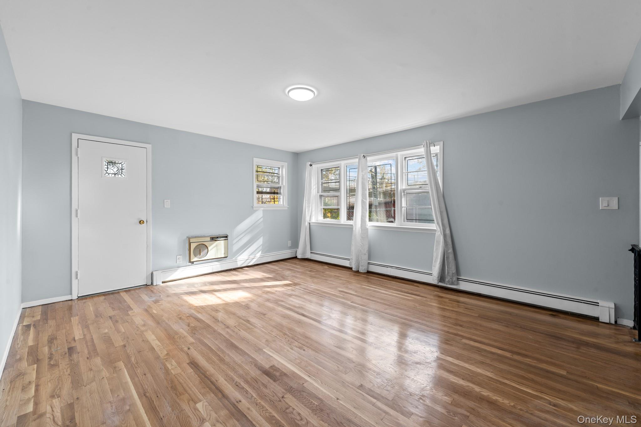 172-11 Horace Harding Expressway Queens, NY 11365 - Photo 3 of 17 a view of an empty room with wooden floor and a window