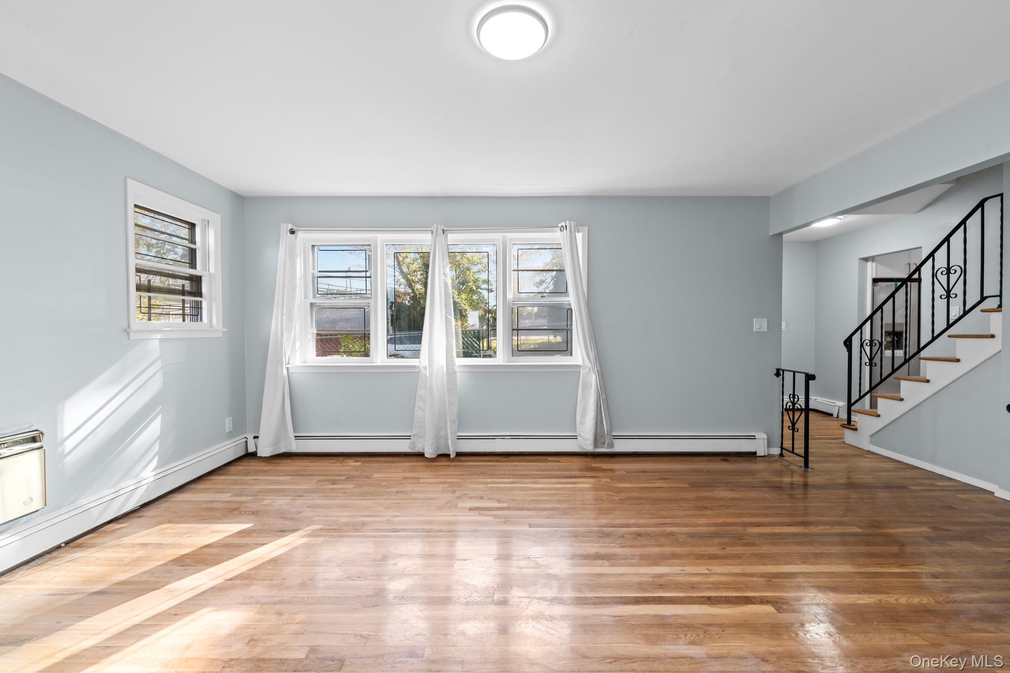 172-11 Horace Harding Expressway Queens, NY 11365 - Photo 5 of 17 a view of an empty room with wooden floor and a window