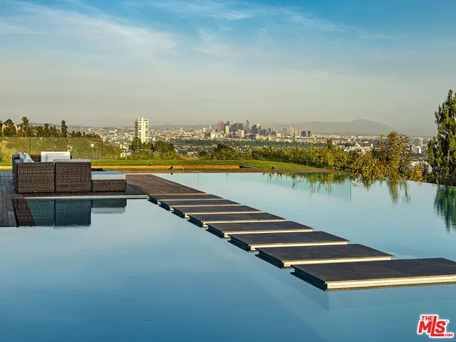 a view of swimming pool with lawn chairs and plants