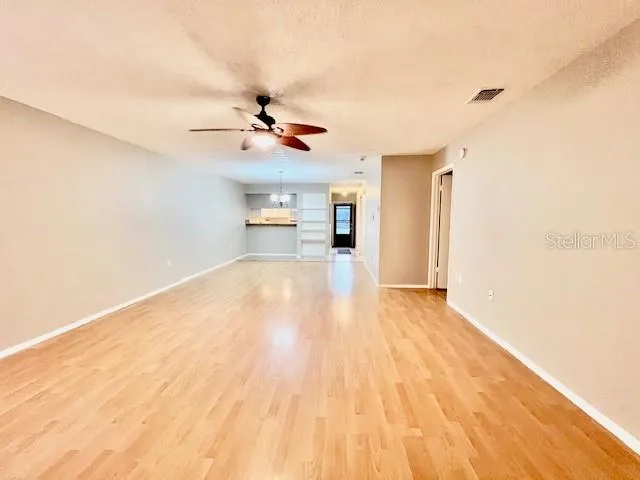 a view of a room with a chandelier fan and wooden floor