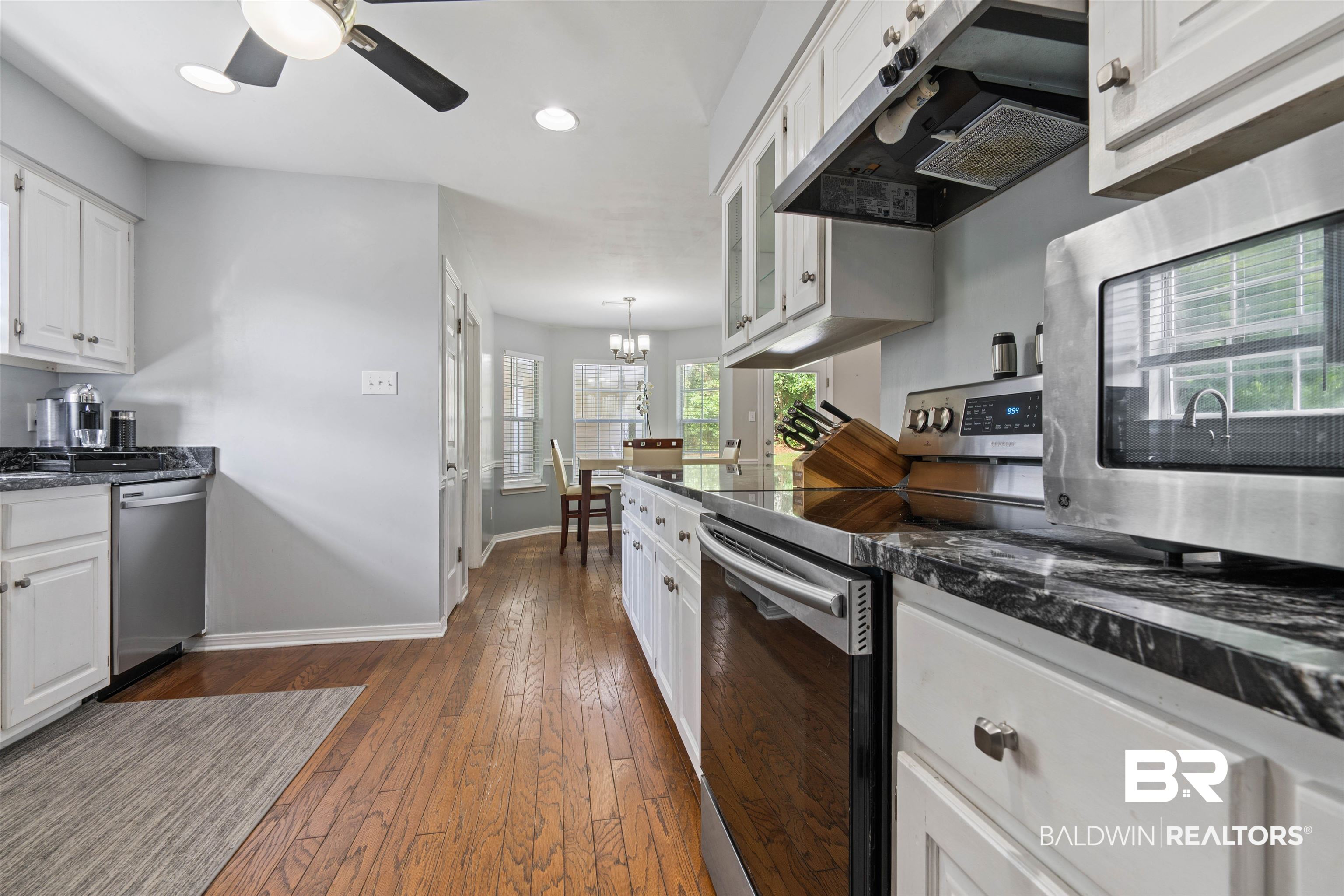 6457 Double Tree Court Mobile, AL 36695 - Photo 7 of 37 Kitchen featuring dark stone countertops, dark wood-type flooring, ceiling fan with notable chandelier, white cabinetry, and appliances with stainless steel finishes