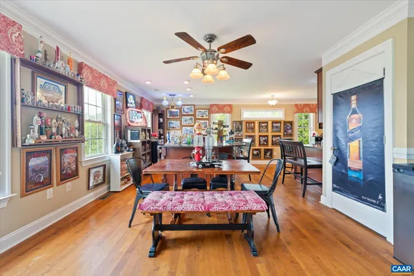 a kitchen with stainless steel appliances granite countertop a refrigerator a stove a sink a dining table and chairs with wooden floor