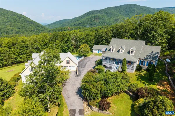 an aerial view of a house with swimming pool and large trees