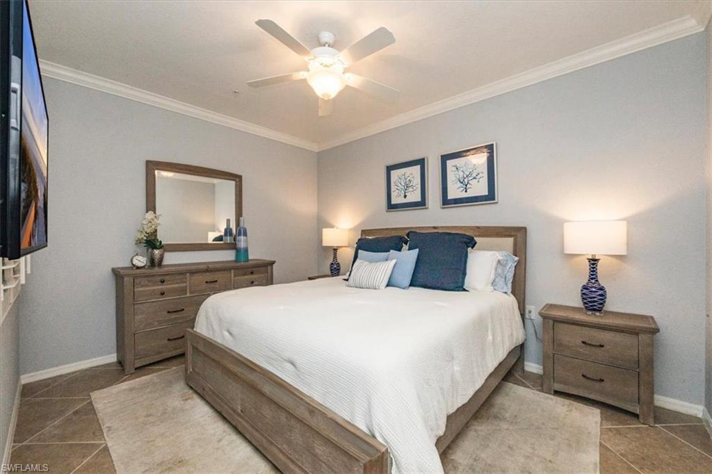9566 Trevi Court, Unit 4942 Naples, FL 34113 - Photo 12 of 31 a bedroom with a large bed and a chandelier