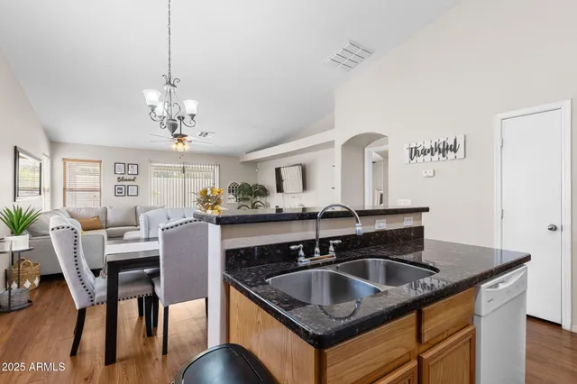 a kitchen island with granite countertop a sink cabinetry and dining table
