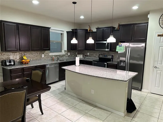 a kitchen with a sink a stove a refrigerator and chairs