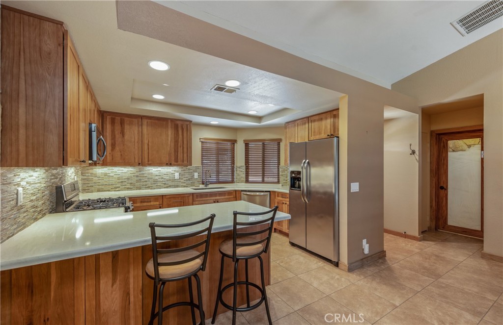 42002 Sand Dune Drive Palm Desert, CA 92211 - Photo 8 of 25 a kitchen with stainless steel appliances granite countertop a table chairs sink and refrigerator