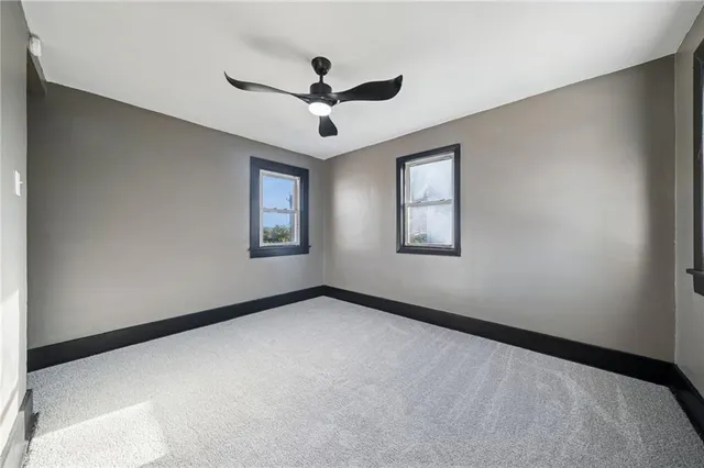 a view of a big room with windows and ceiling fan