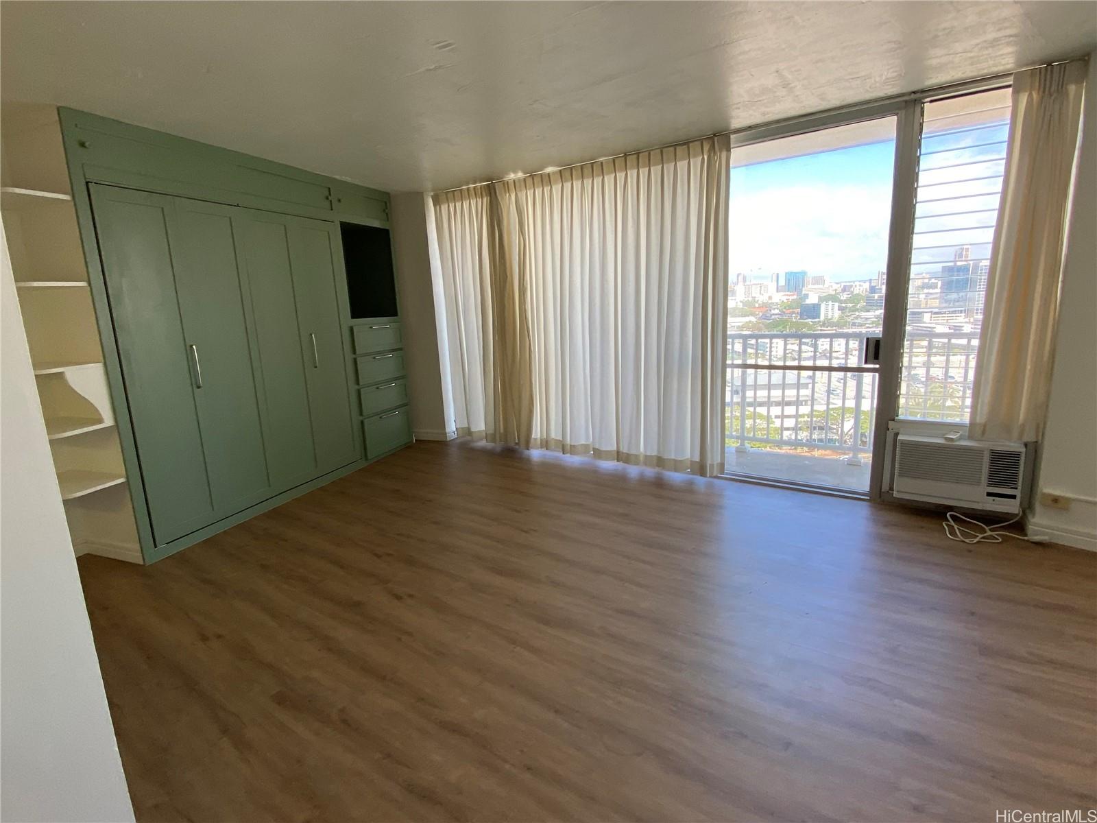 750 Amana Street, Unit 1602 Honolulu, HI 96814 - Photo 4 of 8 an empty room with wooden floor and windows with curtains