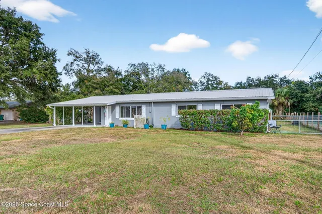 a front view of house with yard and trees in the background