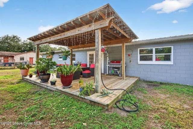 a view of a patio with table and chairs potted plants and floor to ceiling window