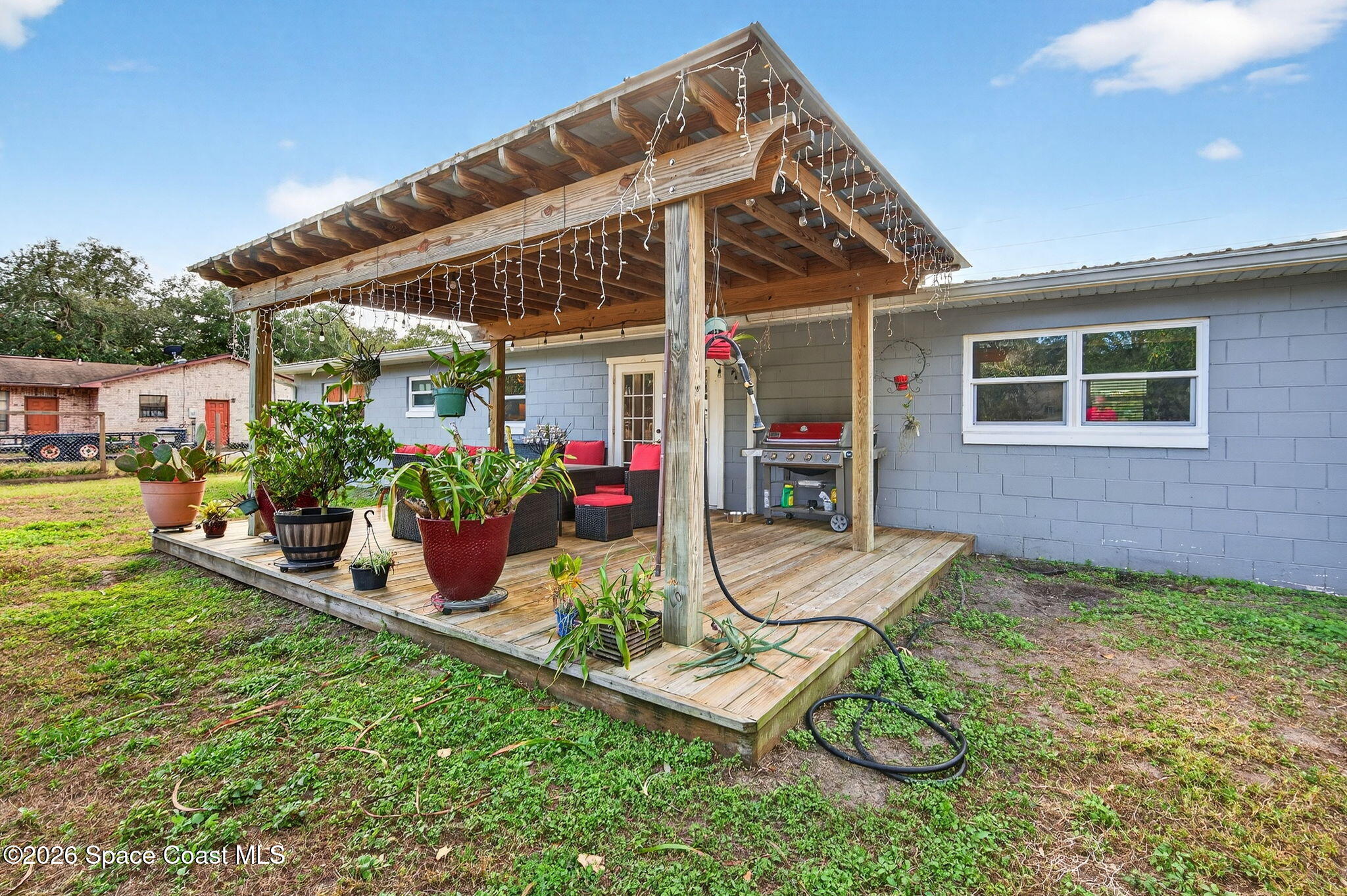 6033 Palm Street Mims, FL 32754 - Photo 31 of 44 a view of a patio with table and chairs potted plants and floor to ceiling window