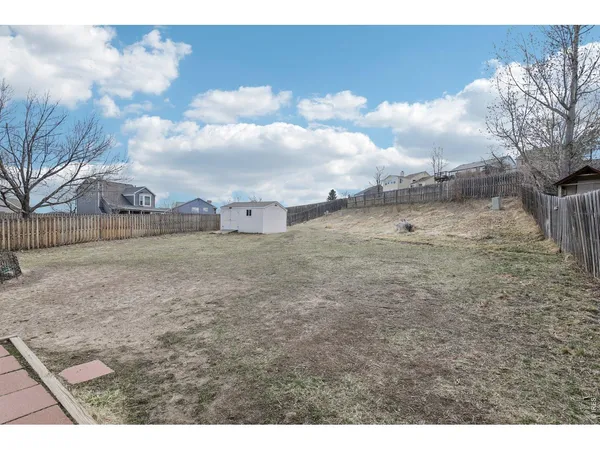 a view of a dry yard with wooden fence