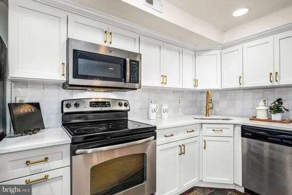 a kitchen with white cabinets and appliances