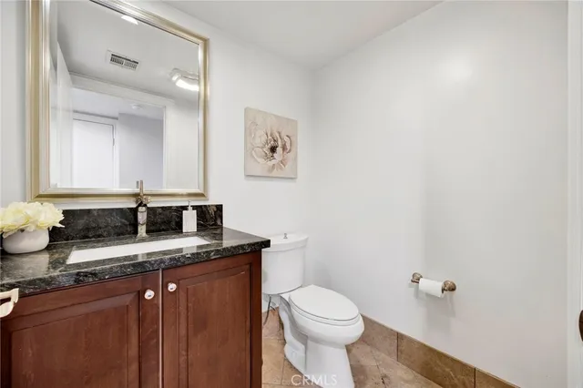a bathroom with a granite countertop sink a toilet and mirror