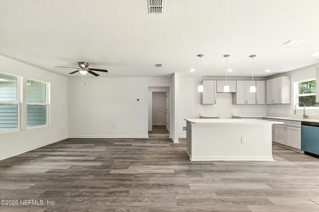 an empty room with wooden floor and ceiling fan