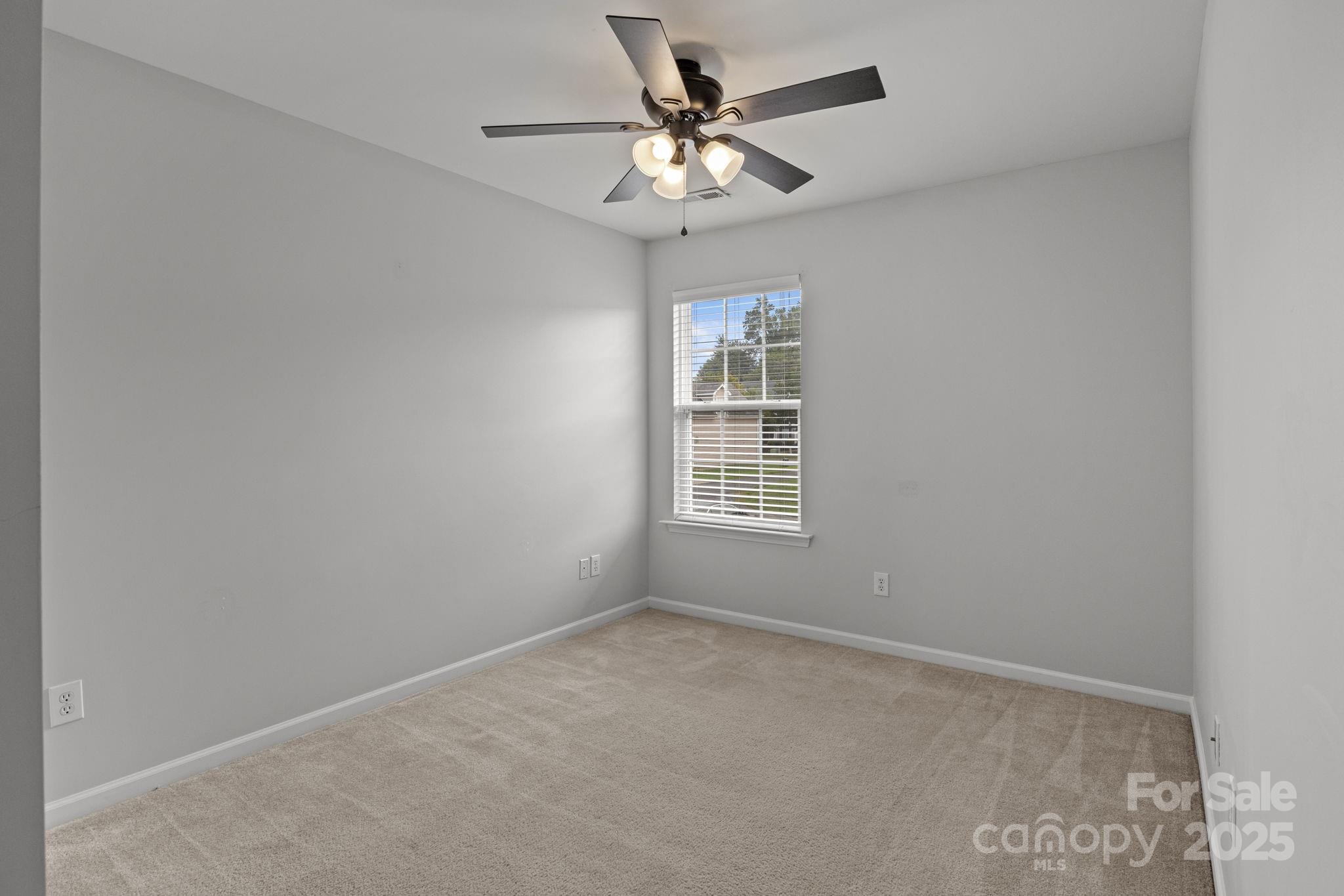 17744 Trolley Crossing Way Cornelius, NC 28031 - Photo 16 of 27 an empty room with a chandelier fan and windows