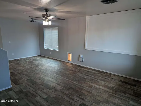 a view of an empty room with wooden floor and a window