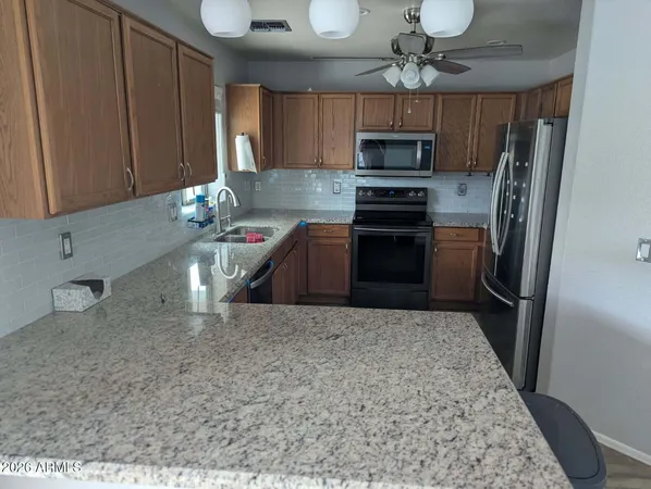 a kitchen with granite countertop a refrigerator stove and microwave