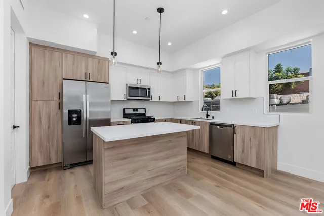 a kitchen with kitchen island granite countertop a sink a counter top space stainless steel appliances and cabinets